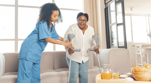 A nurse helping a woman with crutches in a living room - Caryfy App for Caregiver